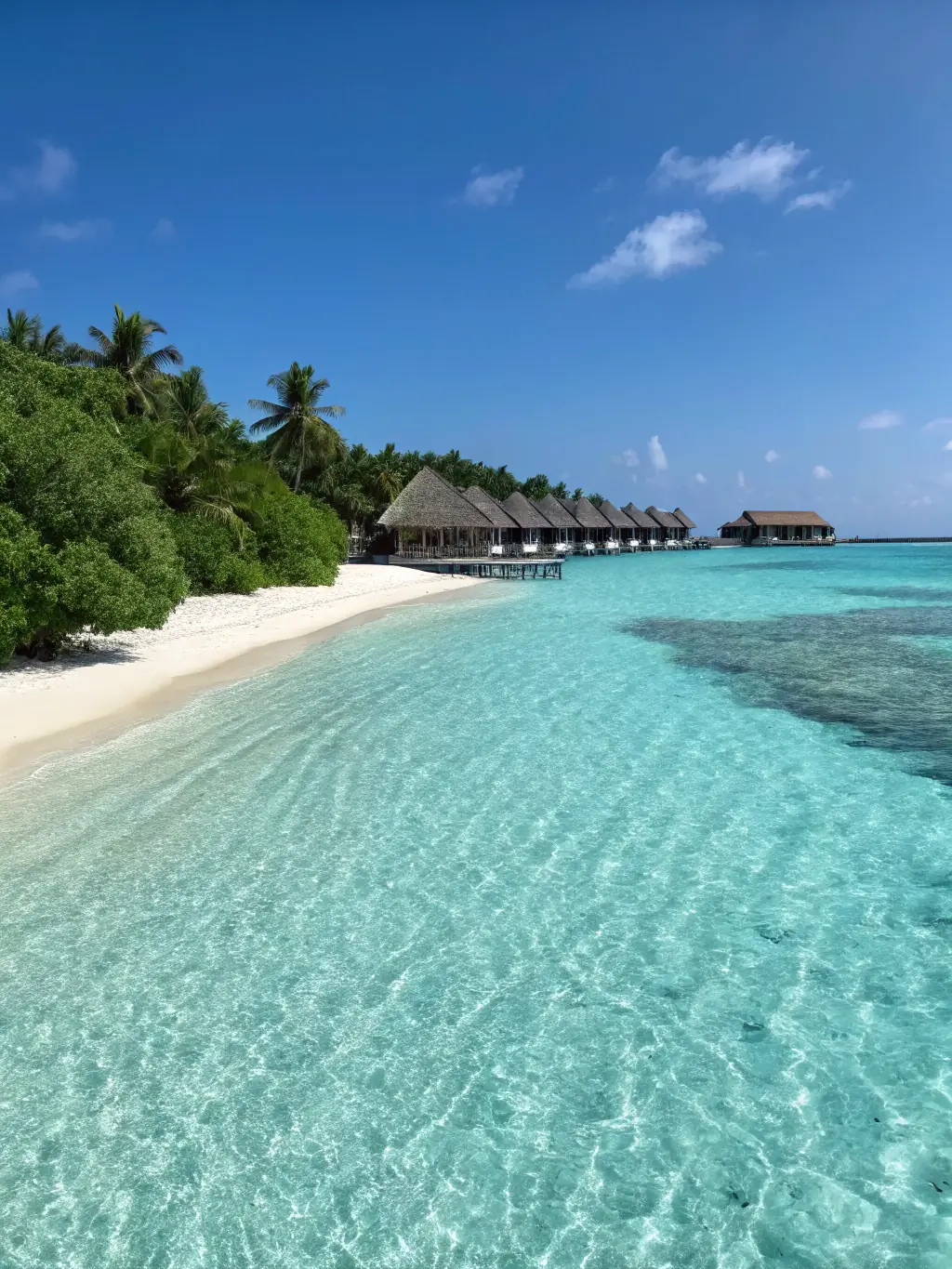 A scenic shot of a luxurious overwater bungalow in the Maldives, with crystal-clear turquoise waters and a private deck. The image conveys a sense of tranquility, exclusivity, and breathtaking natural beauty.